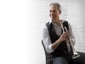 Dan Gosling holding a trumpet in front of brick background